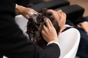 A woman receiving a scalp detox treatment while having her hair washed in a salon.